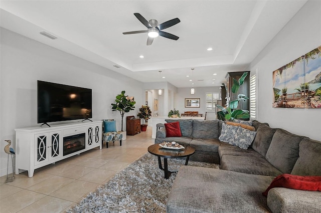 living room featuring light tile patterned floors, a raised ceiling, and ceiling fan