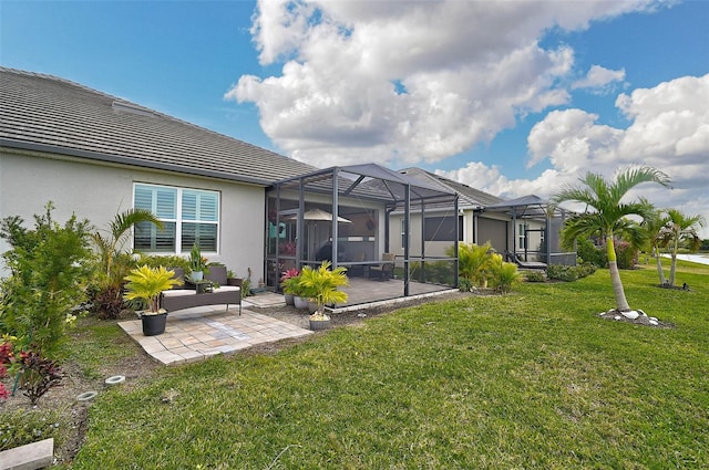 rear view of house with glass enclosure, a patio area, and a lawn