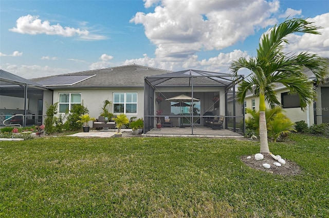 back of property featuring a lawn, glass enclosure, and a patio