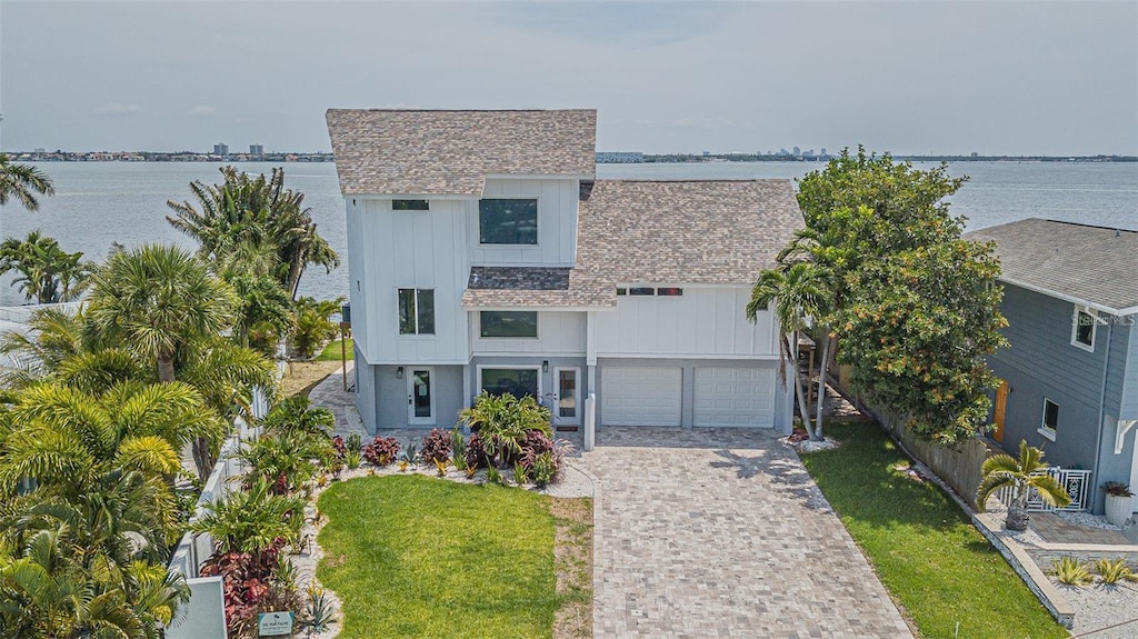 view of front of property featuring a front lawn, a water view, and a garage