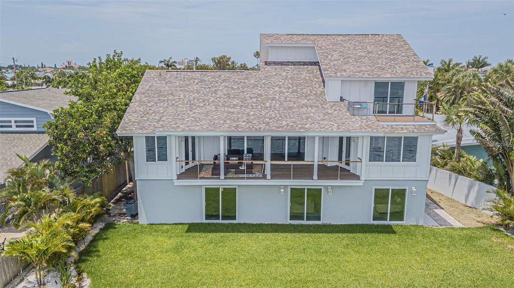 back of property with a balcony and a lawn