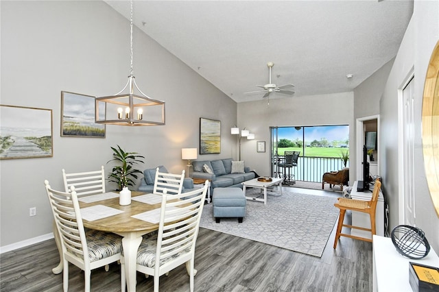 dining room featuring high vaulted ceiling, dark wood-type flooring, and ceiling fan with notable chandelier