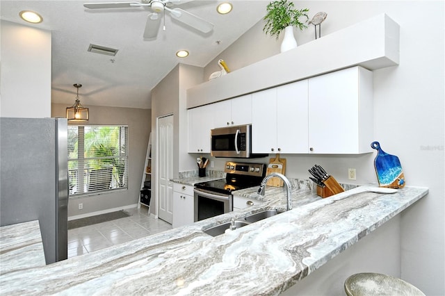 kitchen with kitchen peninsula, appliances with stainless steel finishes, light stone counters, white cabinetry, and lofted ceiling