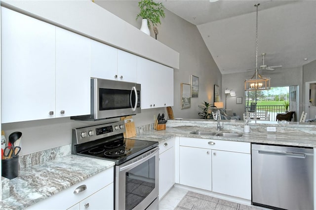 kitchen with lofted ceiling, sink, ceiling fan, appliances with stainless steel finishes, and white cabinetry