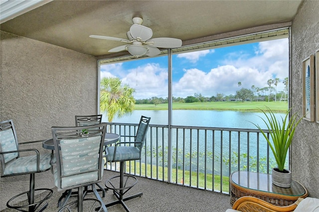 sunroom / solarium featuring a water view and ceiling fan