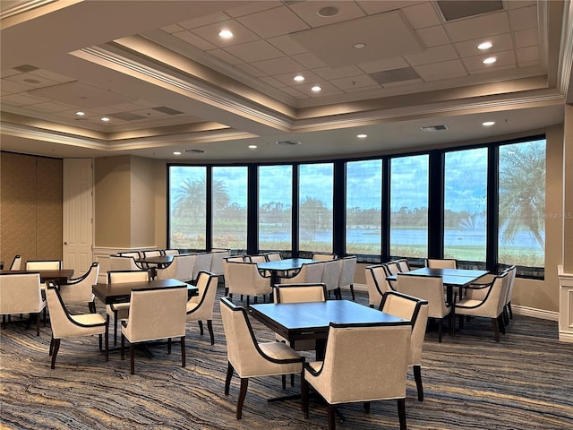 dining room featuring dark carpet, a water view, crown molding, and a tray ceiling