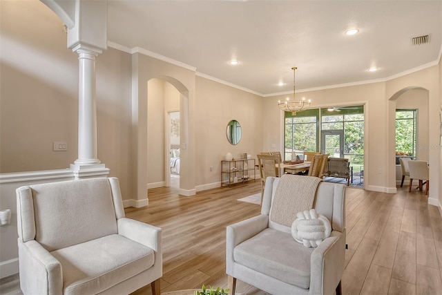 sitting room with decorative columns, an inviting chandelier, ornamental molding, and light hardwood / wood-style flooring