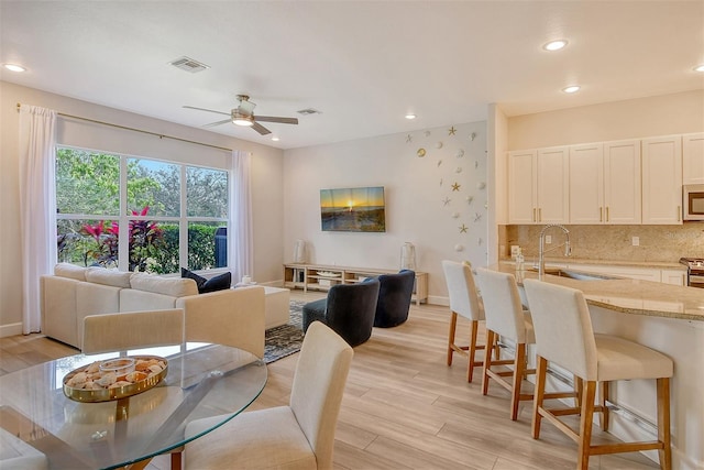 dining area featuring ceiling fan, sink, and light hardwood / wood-style flooring