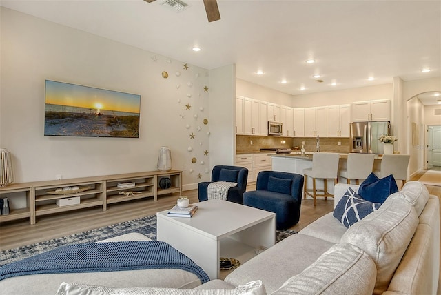 living room with ceiling fan and light hardwood / wood-style flooring