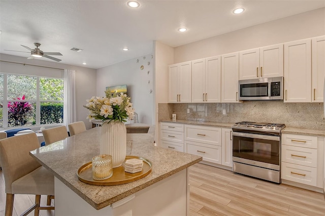 kitchen with light stone countertops, a kitchen bar, appliances with stainless steel finishes, and a center island