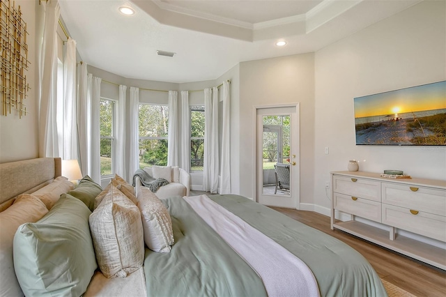 bedroom with access to exterior, crown molding, a raised ceiling, and hardwood / wood-style floors