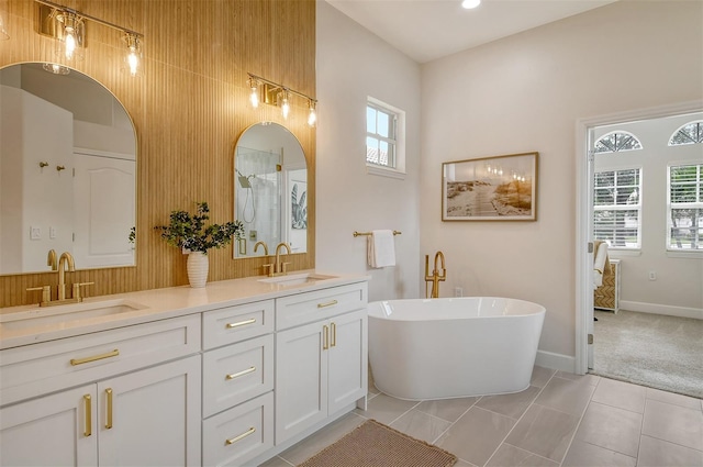 bathroom with a washtub, vanity, wood walls, and tile patterned flooring