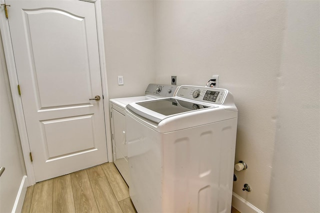 clothes washing area featuring independent washer and dryer and light hardwood / wood-style flooring