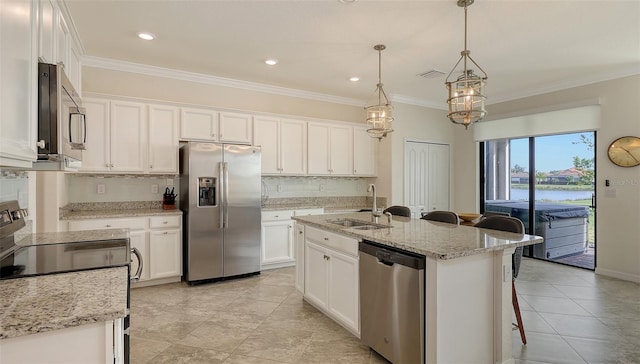 kitchen with white cabinets, stainless steel appliances, an island with sink, hanging light fixtures, and sink