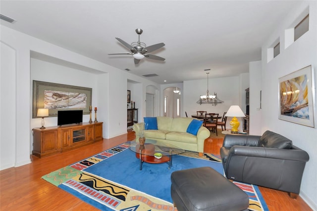 living room featuring ceiling fan with notable chandelier and light hardwood / wood-style floors