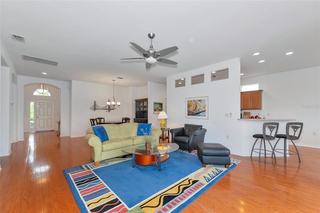 living room with ceiling fan with notable chandelier and light hardwood / wood-style floors