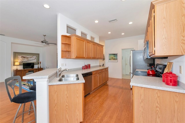 kitchen with kitchen peninsula, light hardwood / wood-style flooring, appliances with stainless steel finishes, sink, and a breakfast bar