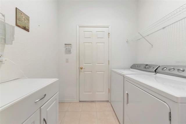 laundry room with cabinets, washing machine and dryer, and light tile patterned floors