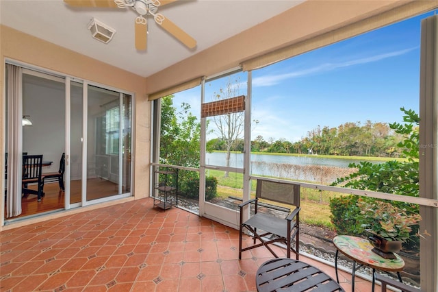 sunroom featuring ceiling fan and a water view