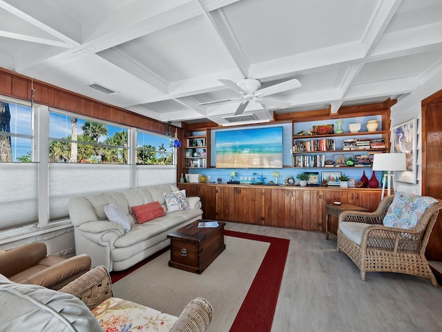 living room with coffered ceiling, beamed ceiling, wooden walls, and light hardwood / wood-style flooring