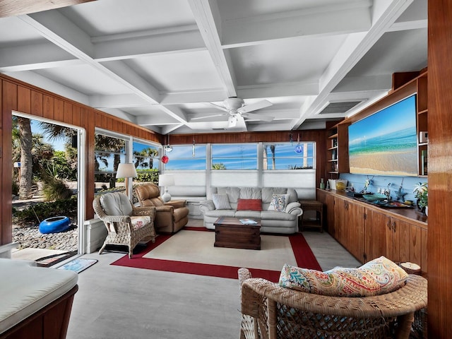 living room featuring wood walls, ceiling fan, beam ceiling, and coffered ceiling