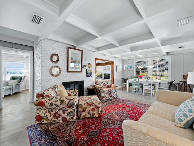 living room featuring a fireplace, beam ceiling, coffered ceiling, and a healthy amount of sunlight