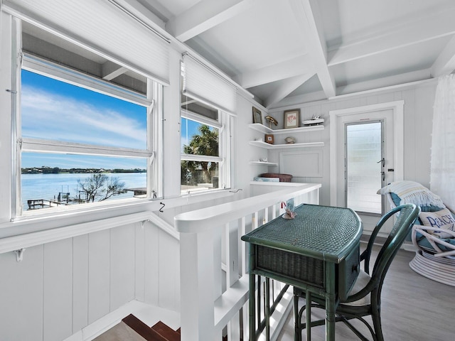 dining area with plenty of natural light, a water view, hardwood / wood-style floors, and beamed ceiling