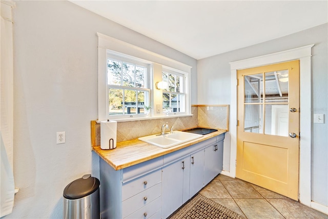 kitchen featuring light tile patterned floors, tasteful backsplash, light countertops, and a sink