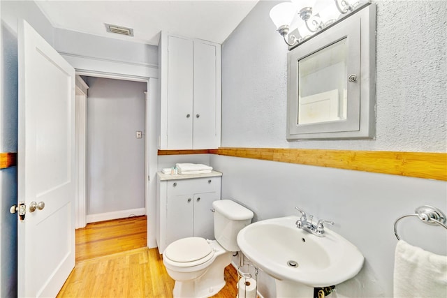 bathroom with hardwood / wood-style flooring, toilet, and sink