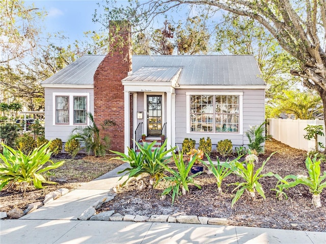 view of front of home featuring metal roof, fence, and a chimney