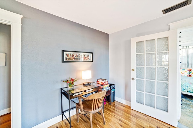 office area with baseboards, visible vents, and light wood finished floors