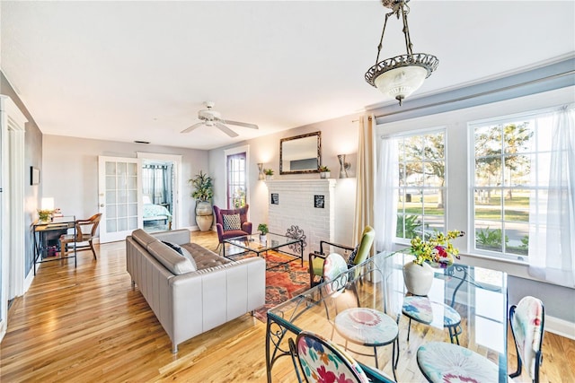 living room featuring a healthy amount of sunlight, a brick fireplace, light wood-style flooring, and ceiling fan