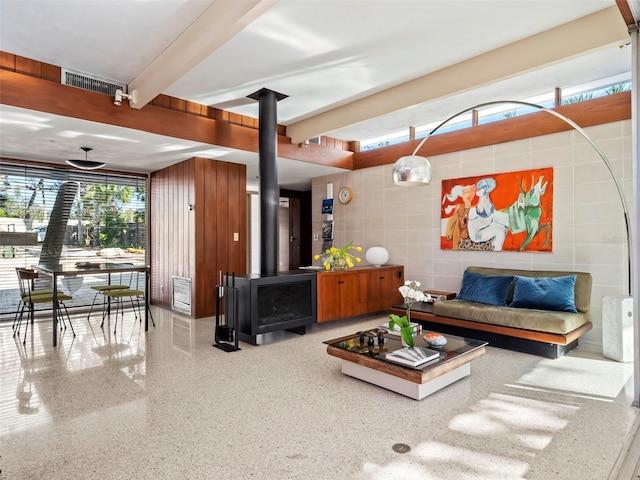 living room with beam ceiling and a wood stove