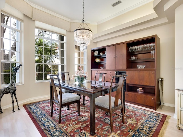 dining room featuring a notable chandelier, a healthy amount of sunlight, crown molding, and light hardwood / wood-style flooring