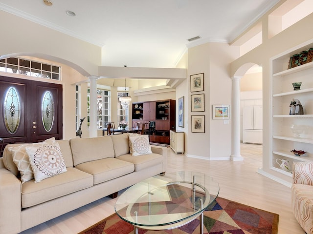 living room featuring light hardwood / wood-style flooring, built in features, ornamental molding, and ornate columns