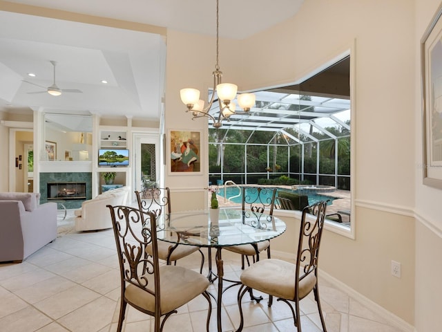 tiled dining area with a fireplace, built in shelves, a tray ceiling, and ceiling fan