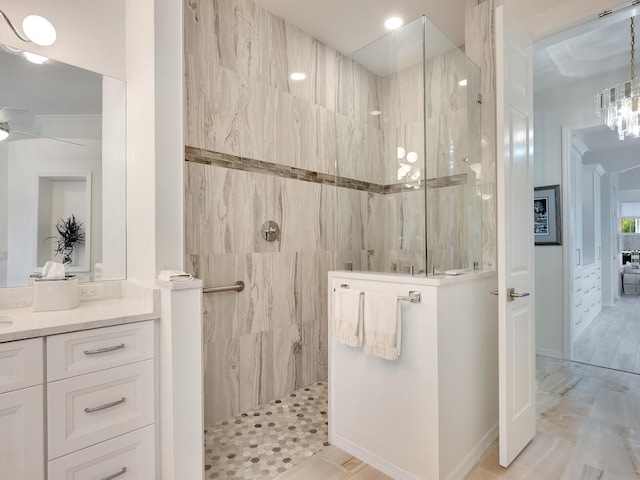 bathroom featuring a tile shower, vanity, and a notable chandelier