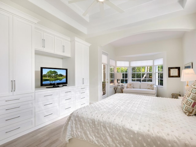 bedroom featuring ceiling fan, light hardwood / wood-style floors, and a high ceiling