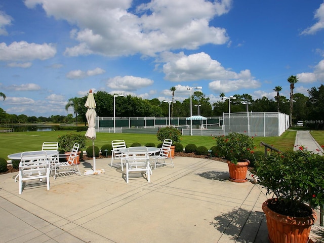 view of patio / terrace with tennis court and a water view