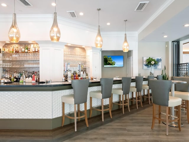 bar with pendant lighting, white cabinetry, ornamental molding, and dark wood-type flooring