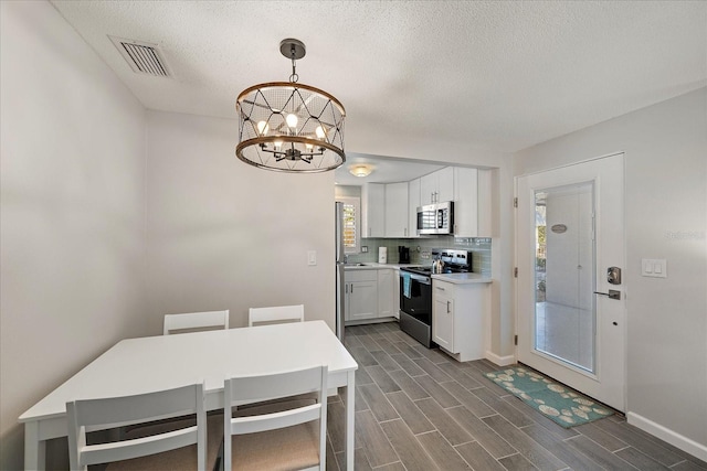 1123 Crescent St Unit 1123/1125, Sarasota, FL 34242 - kitchen with appliances with stainless steel finishes, a chandelier, white cabinets, dark wood finished floors, and a textured ceiling