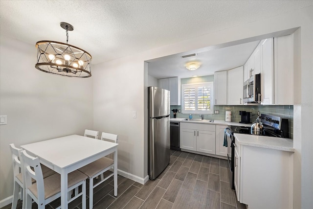 1123 Crescent St Unit 1123/1125, Sarasota, FL 34242 - kitchen with stainless steel appliances, backsplash, a chandelier, light countertops, and dark wood-type flooring
