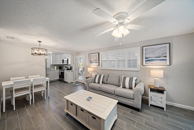 1123 Crescent St Unit 1123/1125, Sarasota, FL 34242 - living room featuring wood tiled floors, baseboards, a ceiling fan, a chandelier, and a textured ceiling