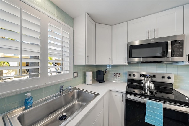 1123 Crescent St Unit 1123/1125, Sarasota, FL 34242 - kitchen with appliances with stainless steel finishes, a sink, light countertops, decorative backsplash, and white cabinetry