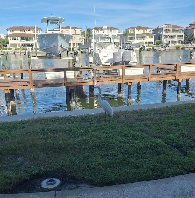 dock area with a lawn and a water view