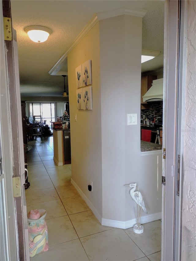 hall featuring ornamental molding, a textured ceiling, and light tile patterned floors