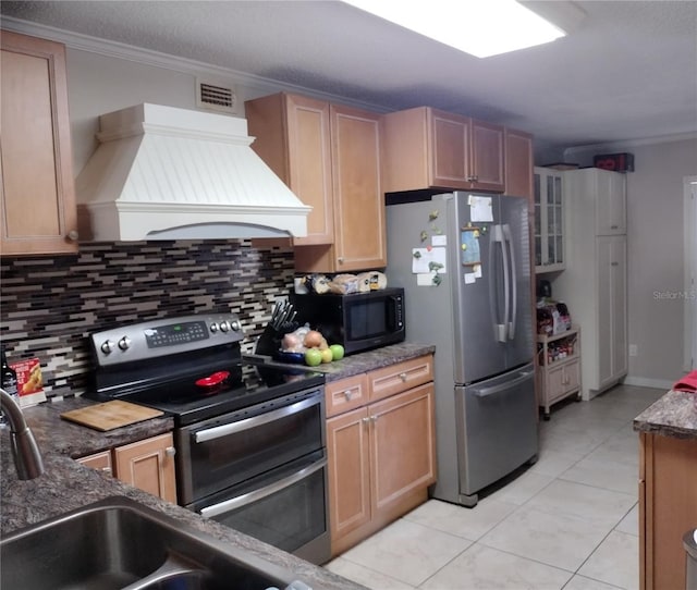 kitchen featuring backsplash, premium range hood, crown molding, light tile patterned floors, and appliances with stainless steel finishes