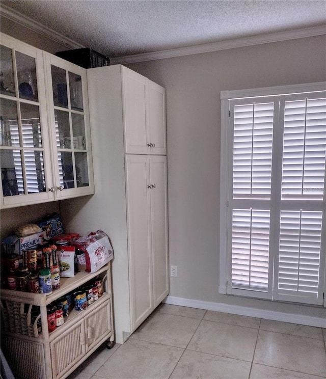 interior space featuring white cabinetry, crown molding, light tile patterned flooring, and a textured ceiling