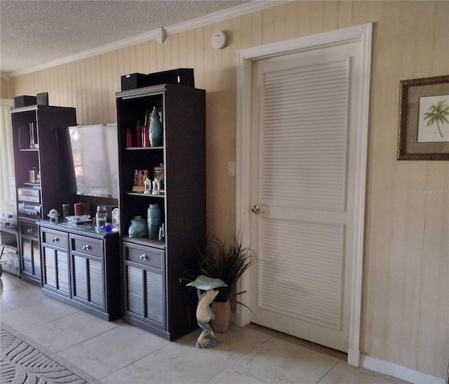 kitchen featuring a textured ceiling, ornamental molding, and light tile patterned flooring