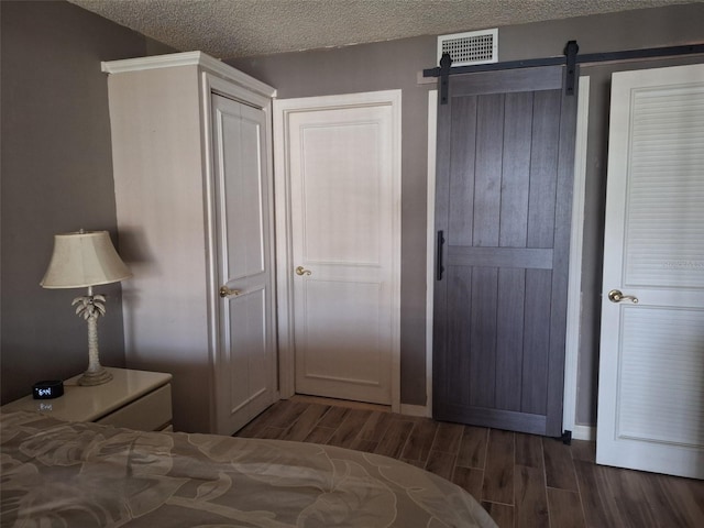 bedroom featuring a barn door, a textured ceiling, and a closet